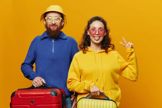 Woman and man smiling, suitcases in hand with yellow and red suitcase smiling merrily and crooked, yellow background, going on a trip, family vacation trip, newlyweds. High quality photo