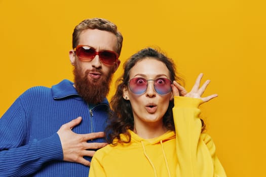 Man and woman couple smiling cheerfully and crooked with glasses, on yellow background, symbols signs and hand gestures, family shoot, newlyweds. High quality photo