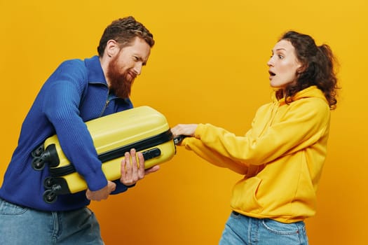 Woman and man smiling, suitcases in hand with yellow and red suitcase smiling merrily and crooked, yellow background, going on a trip, family vacation trip, newlyweds. High quality photo