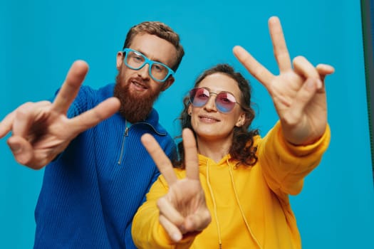 A woman and a man fun couple cranking and showing signs with their hands smiling cheerfully, on a blue background, The concept of a real relationship in a family. High quality photo