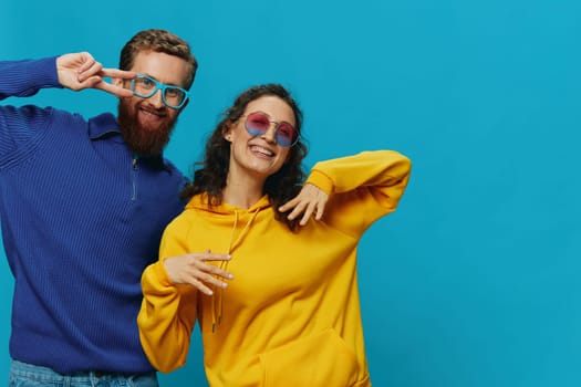 A woman and a man fun couple cranking and showing signs with their hands smiling cheerfully, on a blue background, The concept of a real relationship in a family. High quality photo