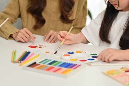 Cropped image of mother drawing with her little daughter, having fun together at home.