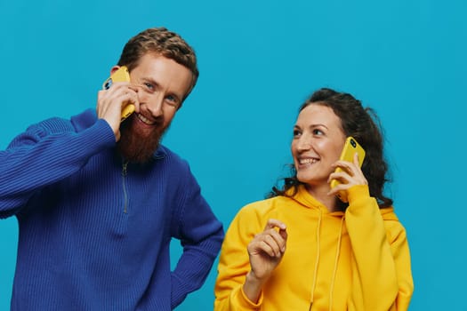 Woman and man cheerful couple with phones in their hands crooked smile cheerful, on blue background. The concept of real family relationships, talking on the phone, work online. High quality photo