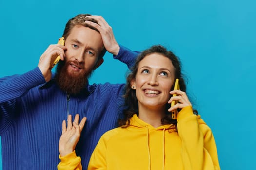 Woman and man cheerful couple with phones in their hands crooked smile cheerful, on blue background. The concept of real family relationships, talking on the phone, work online. High quality photo