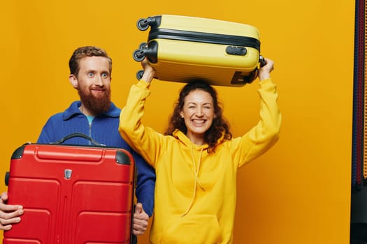 Woman and man smiling, suitcases in hand with yellow and red suitcase smiling merrily and crooked, yellow background, going on a trip, family vacation trip, newlyweds. High quality photo