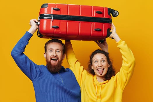 Woman and man smiling, suitcases in hand with yellow and red suitcase smiling merrily and crooked, yellow background, going on a trip, family vacation trip, newlyweds. High quality photo