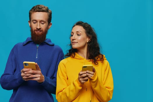 Woman and man cheerful couple with phones in their hands crooked smile cheerful, on blue background. The concept of real family relationships, talking on the phone, work online. High quality photo