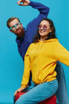 Woman and man smile sitting on suitcase with red suitcase smile, on blue background, packing for trip, family vacation trip. High quality photo