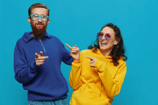 A woman and a man fun couple cranking and showing signs with their hands smiling cheerfully, on a blue background, The concept of a real relationship in a family. High quality photo