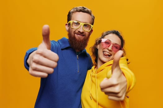 Man and woman couple smiling cheerfully and crooked with glasses, on yellow background, symbols signs and hand gestures, family shoot, newlyweds. High quality photo