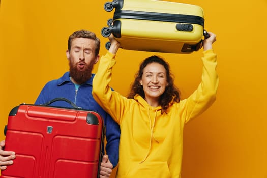 Woman and man smiling, suitcases in hand with yellow and red suitcase smiling merrily and crooked, yellow background, going on a trip, family vacation trip, newlyweds. High quality photo