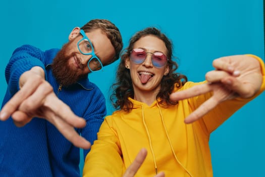 A woman and a man fun couple cranking and showing signs with their hands smiling cheerfully, on a blue background, The concept of a real relationship in a family. High quality photo