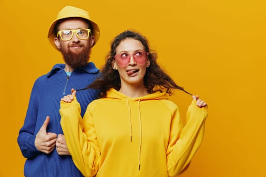 Woman and man smiling, suitcases in hand with yellow and red suitcase smiling merrily and crooked, yellow background, going on a trip, family vacation trip, newlyweds. High quality photo