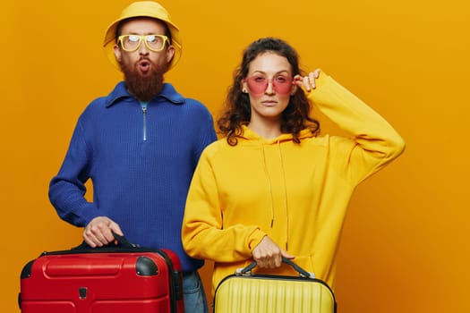 Woman and man smiling, suitcases in hand with yellow and red suitcase smiling merrily and crooked, yellow background, going on a trip, family vacation trip, newlyweds. High quality photo