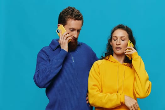 Woman and man cheerful couple with phones in their hands crooked smile cheerful, on blue background. The concept of real family relationships, talking on the phone, work online. High quality photo