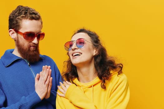 Man and woman couple smiling cheerfully and crooked with glasses, on yellow background, symbols signs and hand gestures, family shoot, newlyweds. High quality photo