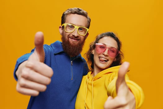 Man and woman couple smiling cheerfully and crooked with glasses, on yellow background, symbols signs and hand gestures, family shoot, newlyweds. High quality photo