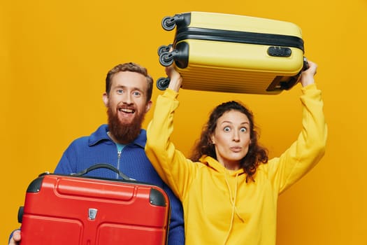 Woman and man smiling, suitcases in hand with yellow and red suitcase smiling merrily and crooked, yellow background, going on a trip, family vacation trip, newlyweds. High quality photo