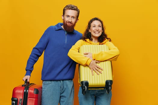 Woman and man smiling, suitcases in hand with yellow and red suitcase smiling merrily and crooked, yellow background, going on a trip, family vacation trip, newlyweds. High quality photo