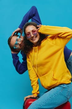 Woman and man smile sitting on suitcase with red suitcase smile, on blue background, packing for trip, family vacation trip. High quality photo