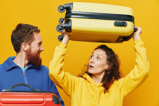 Woman and man smiling, suitcases in hand with yellow and red suitcase smiling merrily and crooked, yellow background, going on a trip, family vacation trip, newlyweds. High quality photo