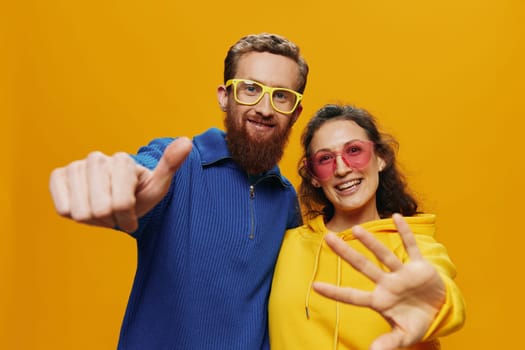 Man and woman couple smiling cheerfully and crooked with glasses, on yellow background, symbols signs and hand gestures, family shoot, newlyweds. High quality photo