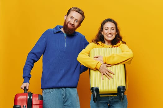 Woman and man smiling, suitcases in hand with yellow and red suitcase smiling merrily and crooked, yellow background, going on a trip, family vacation trip, newlyweds. High quality photo