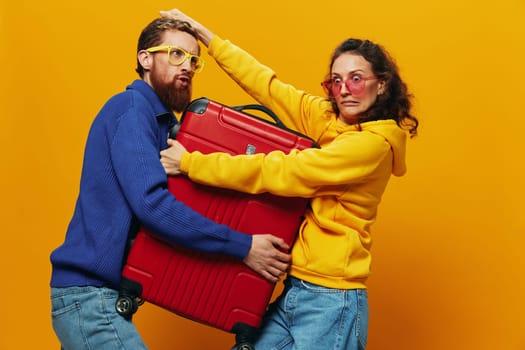 Woman and man smiling, suitcases in hand with yellow and red suitcase smiling merrily and crooked, yellow background, going on a trip, family vacation trip, newlyweds. High quality photo