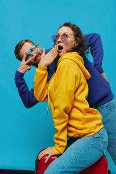 Woman and man smile sitting on suitcase with red suitcase smile, on blue background, packing for trip, family vacation trip. High quality photo