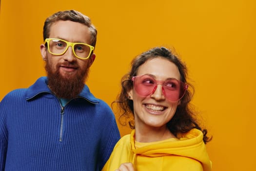 Man and woman couple smiling cheerfully and crooked with glasses, on yellow background, symbols signs and hand gestures, family shoot, newlyweds. High quality photo