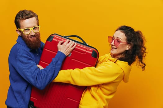 Woman and man smiling, suitcases in hand with yellow and red suitcase smiling merrily and crooked, yellow background, going on a trip, family vacation trip, newlyweds. High quality photo