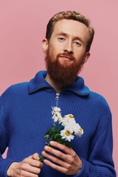 Portrait of a funny man smiling with a bouquet of flowers daisies on pink isolated background, copy place. Holiday concept and congratulations, Valentine's Day, Women's Day. High quality photo