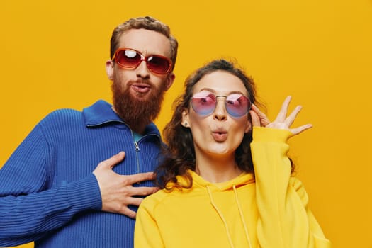 Man and woman couple smiling cheerfully and crooked with glasses, on yellow background, symbols signs and hand gestures, family shoot, newlyweds. High quality photo