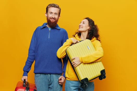 Woman and man smiling, suitcases in hand with yellow and red suitcase smiling merrily and crooked, yellow background, going on a trip, family vacation trip, newlyweds. High quality photo