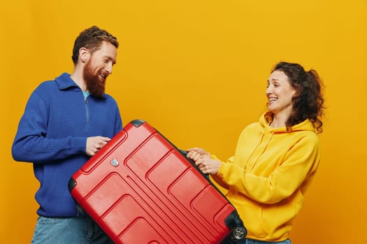 Woman and man smiling, suitcases in hand with yellow and red suitcase smiling merrily and crooked, yellow background, going on a trip, family vacation trip, newlyweds. High quality photo