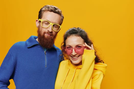 Man and woman couple smiling cheerfully and crooked with glasses, on yellow background, symbols signs and hand gestures, family shoot, newlyweds. High quality photo