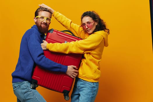 Woman and man smiling, suitcases in hand with yellow and red suitcase smiling merrily and crooked, yellow background, going on a trip, family vacation trip, newlyweds. High quality photo