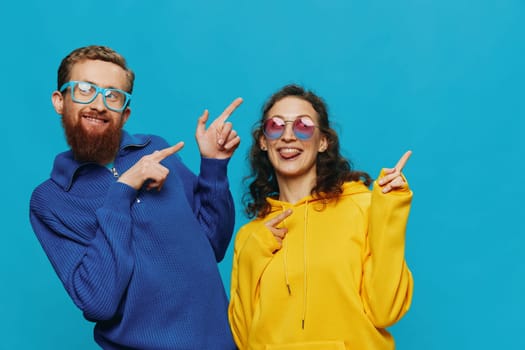 A woman and a man fun couple cranking and showing signs with their hands smiling cheerfully, on a blue background, The concept of a real relationship in a family. High quality photo