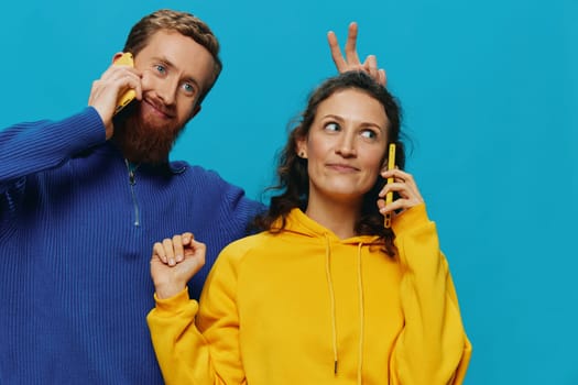 Woman and man cheerful couple with phones in their hands crooked smile cheerful, on blue background. The concept of real family relationships, talking on the phone, work online. High quality photo