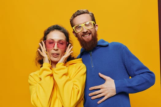 Man and woman couple smiling cheerfully and crooked with glasses, on yellow background, symbols signs and hand gestures, family shoot, newlyweds. High quality photo