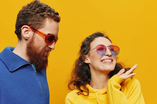 Man and woman couple smiling cheerfully and crooked with glasses, on yellow background, symbols signs and hand gestures, family shoot, newlyweds. High quality photo