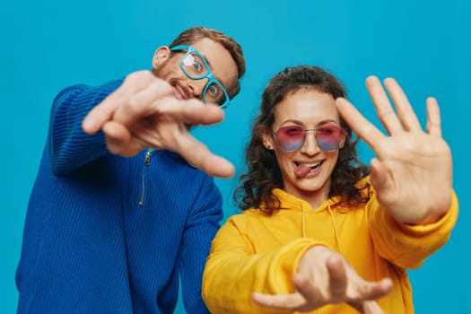 A woman and a man fun couple cranking and showing signs with their hands smiling cheerfully, on a blue background, The concept of a real relationship in a family. High quality photo