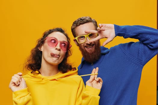 Man and woman couple smiling cheerfully and crooked with glasses, on yellow background, symbols signs and hand gestures, family shoot, newlyweds. High quality photo