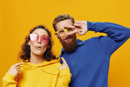 Man and woman couple smiling cheerfully and crooked with glasses, on yellow background, symbols signs and hand gestures, family shoot, newlyweds. High quality photo