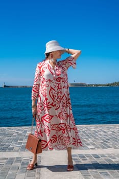 woman in a hat and dress enjoys the blue sea and summer. Welcome summer