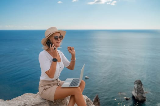 Freelance women sea working on the computer. Good looking middle aged woman typing on a laptop keyboard outdoors with a beautiful sea view. The concept of remote work