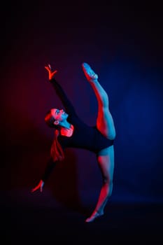 A girl gymnast in a swimsuit does tricks on white and dark background. Front view