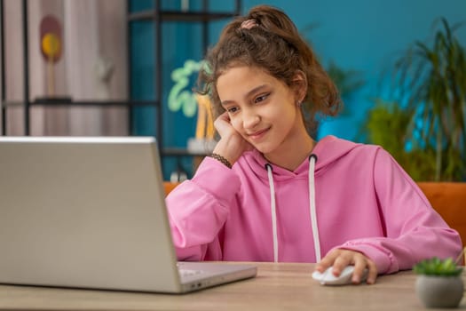 Caucasian preteen school girl using laptop for online lesson, doing homework. Distance learning education. Young child, kid at home workplace sitting at the table. Video call by webcam on internet
