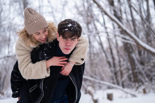 A young couple walks in the park in winter. Guy and girl hugging outdoors