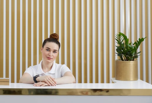 Female receptionist at reception desk in modern office lobby